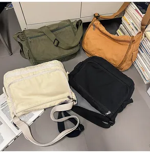 Flat lay of multiple washed canvas messenger bags in green, khaki, beige, and black colors