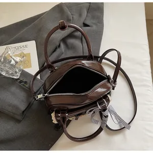 Détail du sac à main marron foncé brillant avec bordure en dentelle et ruban à carreaux