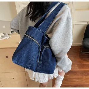 Detail of blue denim tote bag with metal zippers and long drawstrings in home office setting