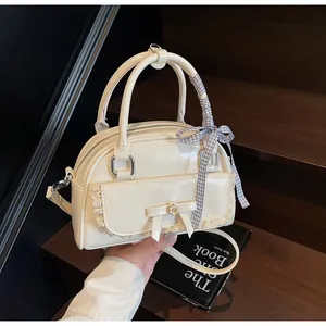 Détail d'un sac Boston blanc crème avec dentelle, nœud et poignée avec ruban