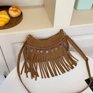Détail d'un sac bohème en daim marron avec sangle ethnique et franges de pièces