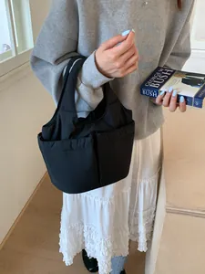 Sac seau matelassé noir minimaliste avec deux poches avant et texture en nylon