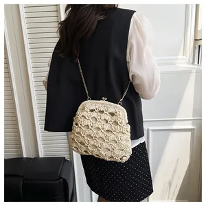 Détail d'un sac bandoulière en paille tissée avec fermoir vintage et chaîne dorée