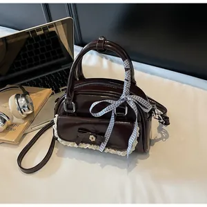 Détail du sac en cuir PU marron brillant avec nœud en dentelle et ruban de soie à carreaux