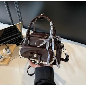 Détail du mini sac marron foncé avec dentelle, nœud et ruban à carreaux sur la poignée