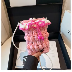 Detail of pink and white crochet phone bag featuring 3D textures and a pearl button