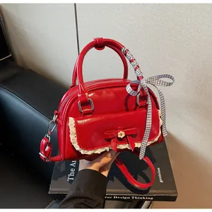 Détail du sac à main rouge avec dentelle, nœud décoratif et ruban à carreaux sur la poignée