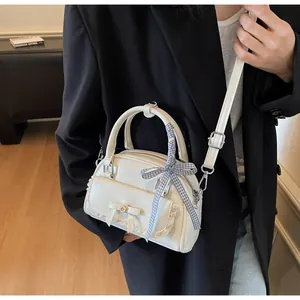 Détail du sac à main blanc crème avec bordure en dentelle et nœud en ruban à carreaux chic