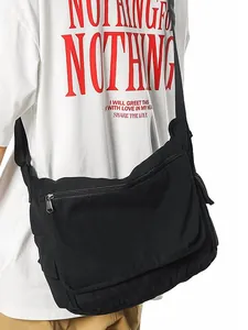 Black washed canvas messenger bag for commuting, showing side view on male model