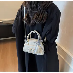 Détail du sac à main blanc crème avec décoration de nœud et ruban en soie à carreaux