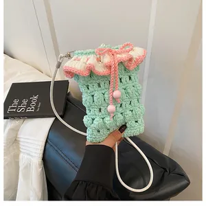 Close-up of green crochet phone bag with pink ruffle trim and drawstring detail