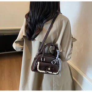 Gros plan d'un mini sac marron avec bordure en dentelle, nœud et ruban à carreaux sur l'anse
