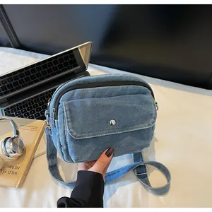 Detail shot of a blue denim crossbody bag with metal buckle and adjustable strap