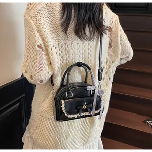 Détail d'un sac à main bowling noir avec nœud et bordure en dentelle blanche sur modèle