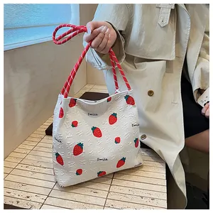Detail of strawberry print tote with white 3D bubble texture and woven rope handle