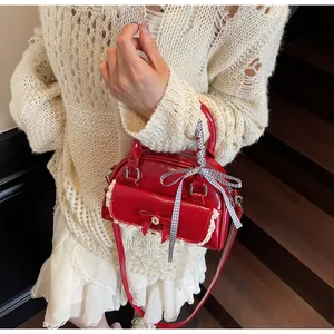Détail du sac à main en cuir verni rouge avec bordure en dentelle et nœud élégant