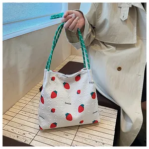 Close-up of quilted strawberry tote with green rope handles and smile print