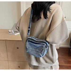Side view of wash blue denim crossbody bag on model in a modern wooden interior