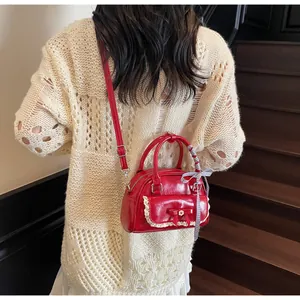 Détail du sac à main rouge avec bordures en dentelle, nœud et poignée en foulard à carreaux