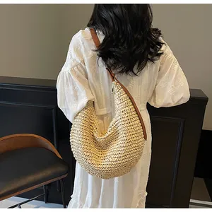 Spacious woven straw hobo bag with brown shoulder strap worn with a white dress