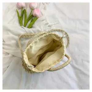 Bovenaanzicht van crème geweven bucket bag met trekkoordinzet en roze tulpen