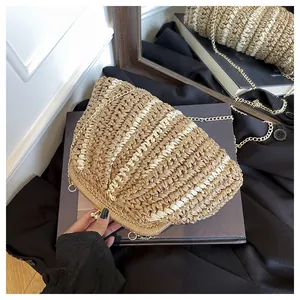Détail de la pochette en paille tressée avec chaîne en métal et motif à rayures