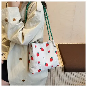 Detailed shot of embossed strawberry pattern and woven rope strap on the white tote bag