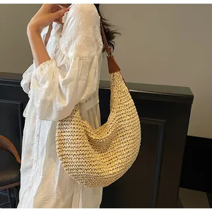 Close-up of woven straw texture and premium brown leather strap on a large beach tote bag
