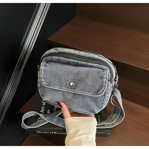 Detail of vintage denim crossbody bag featuring silver buckle and textured blue fabric