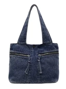 Large blue washed denim tote bag with two front zipper pockets and fringe detail
