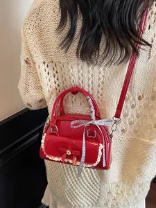 Sac à main en cuir verni rouge avec nœud en dentelle et ruban porté par un mannequin