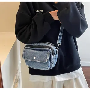 Detailed shot of denim crossbody bag featuring dual zippers and front pocket with metal snap