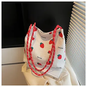Detail of strawberry print on waffle fabric shoulder bag with rope handle