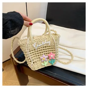 Detail van hol geweven beige strooien tas met pluche bloemen en trekkoordvoering