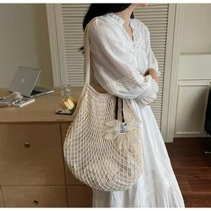 Detailansicht der cremefarbenen Netztasche mit Blumenanhänger und feinem Strickmuster