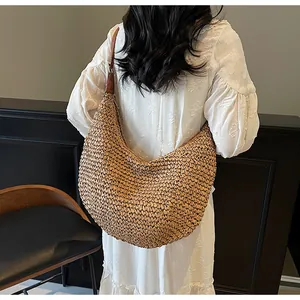 Close-up of a natural woven straw shoulder bag featuring a large crescent hobo design