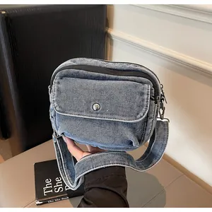 Detail shot of denim crossbody bag with silver metal buckle and adjustable strap