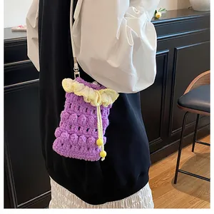 Detail of hand-crocheted purple phone bag with yellow ruffles and wooden bead drawstring