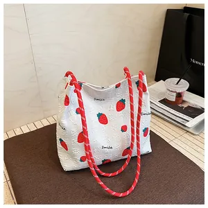 Detailed view of seersucker tote bag with red strawberry prints and woven rope handles