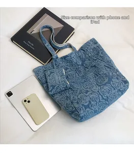 Bolso tote de mezclilla azul con rosas 3D comparado con el tamaño de un iPad