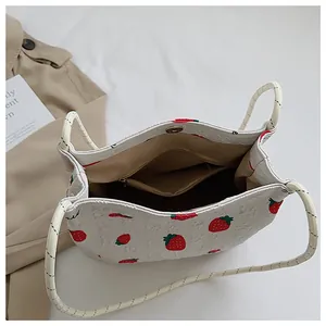 Detail view of the strawberry print handbag showing inner brown lining and a zipper pocket