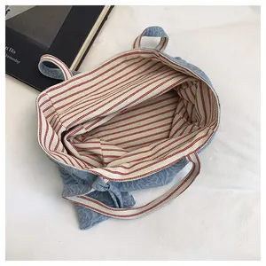 Detalle del bolso tote de jacquard azul claro con rosas y forro de rayas rojas y blancas