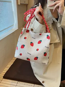 Cute white strawberry print canvas tote bag with woven red handles shown on a model