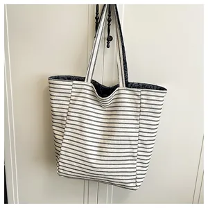 Primer plano de bolsa tote de lona con rayas blancas y negras colgada en pared