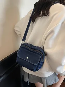 Classic dark blue denim crossbody bag with multiple zippers and wide shoulder strap