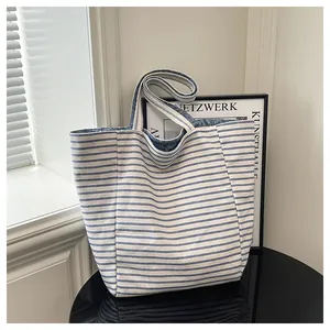 Detalle del bolso de lona a rayas azules con forro de jacquard vaquero con monograma