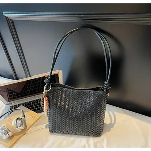 Detailaufnahme der schwarzen gewebten Beuteltasche mit Textur und Holzperlen-Anhänger