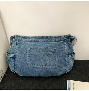 Detail view of washed denim fabric texture and functional front pocket on a large tote bag