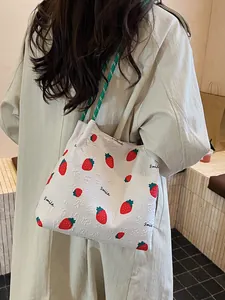 White strawberry print tote bag with green rope handles and smile text on textured fabric