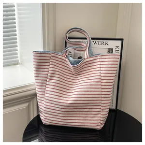 Detalle del bolso de lona a rayas rojas con forro de mezclilla azul claro y asas anchas